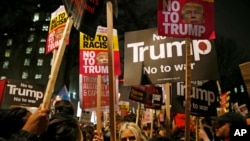 Demonstrators hold banners as they take part in a protest against U.S President Donald Trump's controversial travel ban on refugees and people from seven mainly-Muslim countries, outside Downing Street in London, Monday, Jan. 30, 2017.