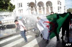 Algerian riot police spray anti-government protesters with water during a demonstration in the capital Algiers, April 9, 2019