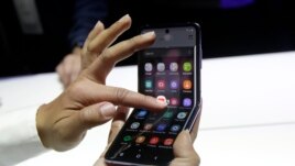 A Samsung worker gives a demonstration of the Galaxy Z Flip Phone at the Unpacked 2020 event in San Francisco, Tuesday, Feb. 11, 2020. (AP Photo/Jeff Chiu)