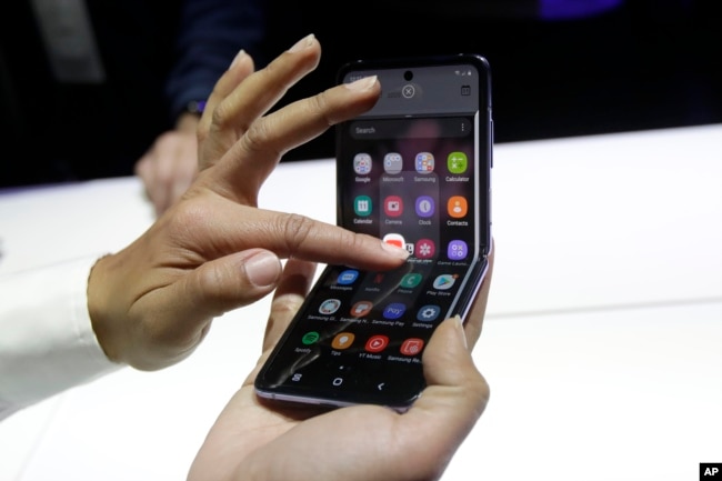 A Samsung worker gives a demonstration of the Galaxy Z Flip Phone at the Unpacked 2020 event in San Francisco, Tuesday, Feb. 11, 2020. (AP Photo/Jeff Chiu)