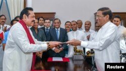 FILE - Sri Lanka's former President Mahinda Rajapaksa, front left, is sworn in as prime minister before President Maithripala Sirisena in Colombo, Sri Lanka, Oct. 26, 2018.