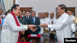 Sri Lanka's former President Mahinda Rajapaksa, front left, is sworn in as prime minister before President Maithripala Sirisena in Colombo, Sri Lanka, Oct. 26, 2018.
