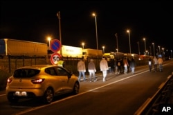 A car of the security society of Eurotunnel follows a group of migrants, in Calais, northern France, Wednesday, July 29, 2015.