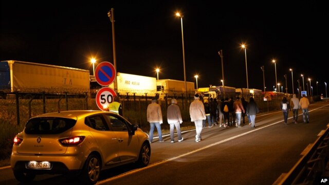 Un automóvil de seguridad de la sociedad del Eurotunnel sigue a un grupo de migrantes, en Calais, norte de Francia, el miércoles, 29 de julio, de 2015.