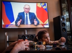 RUSSIA -- A woman watches a live broadcast of Russian President Vladimir Putin's address to the nation over the coronavirus outbreak, in her appartment in Moscow, April 2, 2020