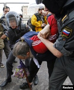 Russian police detain an opposition activist, with the white ribbon as a symbol of protest, during an anti-Kremlin protest in Moscow, May 31, 2012.