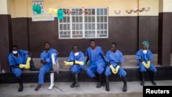 FILE - Health workers rest outside a quarantine zone at a Red Cross facility in the town of Koidu, Kono district, in eastern Sierra Leone, Dec. 19, 2014.