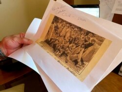 In this July 8, 2021, photo, adjunct history professor and research associate Larry Larrichio holds a copy of a late 19th century photograph of pupils at an Indigenous boarding school in Santa Fe during an interview in Albuquerque, New Mexico.