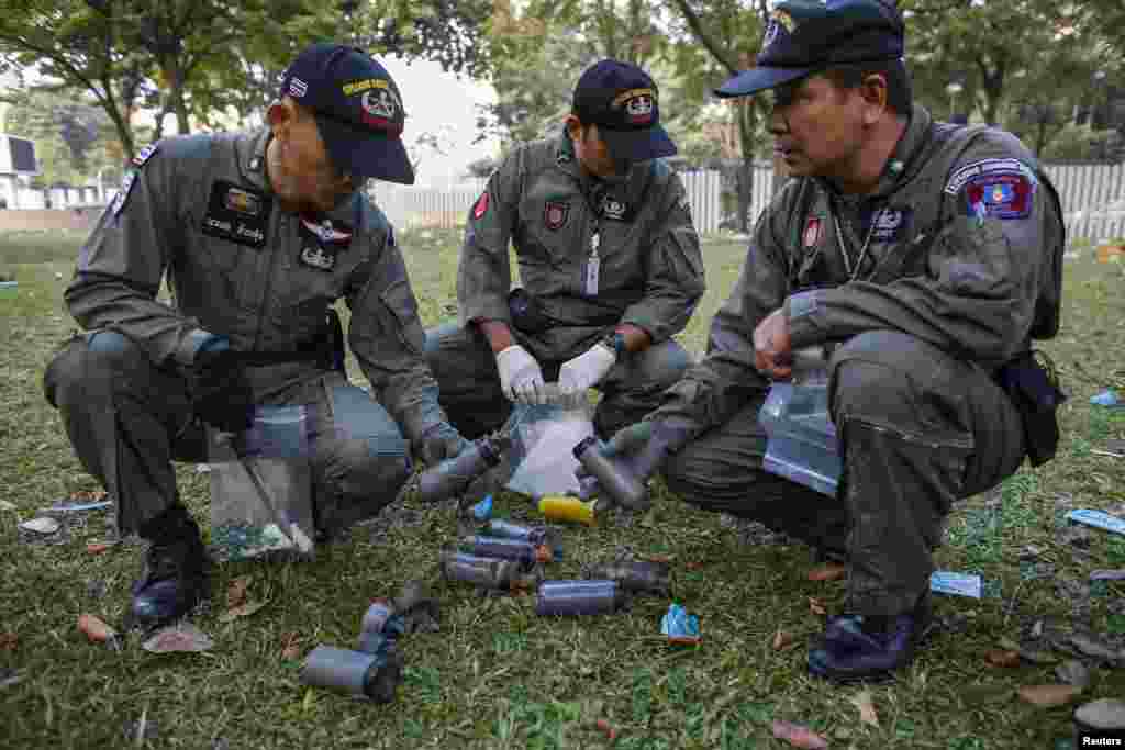 Thai security personnel inspect unidentified objects at the Thai-Japan youth stadium, the site of fierce clashes between anti-government protesters and riot police, in central Bangkok, Thailand, Dec. 27, 2013.