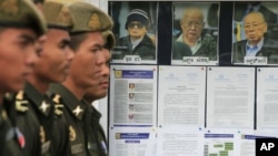 Cambodian military officials line up in front the top leaders of Khmer Rouge portraits, from right, former Khmer Rouge Foreign Minister Ieng Sary, former Khmer Rouge head of state Khieu Samphan, and former Deputy Secretary Nuon Chea, during the second day of trial of the U.N.-backed war crimes tribunal in Phnom Penh, Cambodia, Tuesday, Dec. 6, 2011. Three senior leaders of Cambodia's brutal Khmer Rouge regime on Tuesday continue to be questioned at the U.N.-backed tribunal over their roles in the deaths of an estimated 1.7 million people when their movement held power in the 1970s. (AP Photo/Heng Sinith)