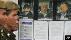 Cambodian military officials line up in front the top leaders of Khmer Rouge portraits, from right, former Khmer Rouge Foreign Minister Ieng Sary, former Khmer Rouge head of state Khieu Samphan, and former Deputy Secretary Nuon Chea, during the second day of trial of the U.N.-backed war crimes tribunal in Phnom Penh, Cambodia, Tuesday, Dec. 6, 2011. Three senior leaders of Cambodia's brutal Khmer Rouge regime on Tuesday continue to be questioned at the U.N.-backed tribunal over their roles in the deaths of an estimated 1.7 million people when their movement held power in the 1970s. (AP Photo/Heng Sinith)