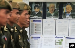 Cambodian military officials line up in front the top leaders of Khmer Rouge portraits, from right, former Khmer Rouge Foreign Minister Ieng Sary, former Khmer Rouge head of state Khieu Samphan, and former Deputy Secretary Nuon Chea, during the second day of trial of the U.N.-backed war crimes tribunal in Phnom Penh, Cambodia, Tuesday, Dec. 6, 2011.