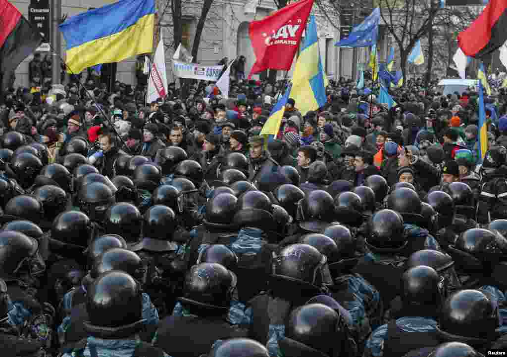 Police stand guard in front of protesters during a demonstration in support of EU integration in front of parliament in Kyiv, Dec. 3, 2013.