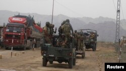 A soldier gestures as he stands beside his comrade in a vehicle headed toward North Waziristan, from Bannu, June 19, 2014.