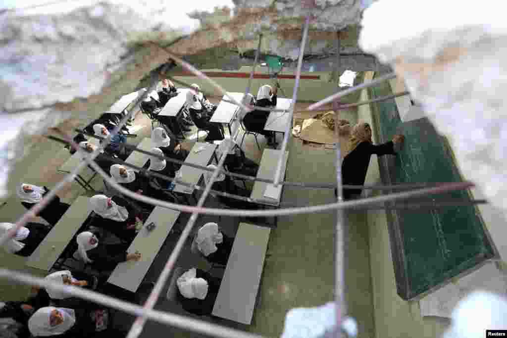 Palestinian schoolgirls, pictured through a hole in the roof of a classroom, attend a lesson on the first day of a new school year at Suhada Khouza school in Khan Younis in the southern Gaza Strip. Witnesses said the classroom was damaged by Israeli shelling during a 50-day war last summer.