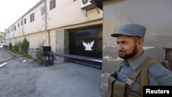 An Afghan policeman guards the gate of a guesthouse after an attack the previous night in which 14 civilians were killed, in Kabul, May 14, 2015. 