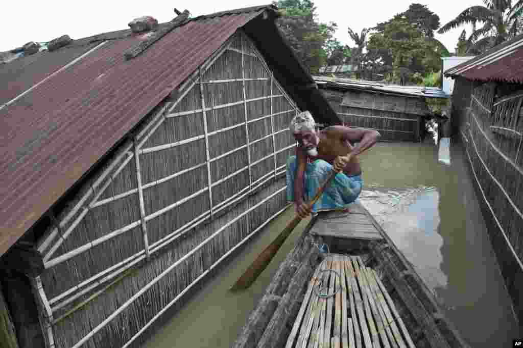 An elderly man rows a boat past flooded houses at Sildubi village, in the northeastern Indian state of Assam. Torrential monsoon rains have caused widespread flooding in Assam state and forced around 1.2 million people to leave their water-logged homes.