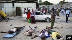 EDS NOTE: GRAPHIC CONTENT - Somalis observe the bodies of victims of a suicide car bomb attack in the capital Mogadishu, Somalia, Wednesday, Feb. 8, 2012. (AP Photo/Farah Abdi Warsameh)