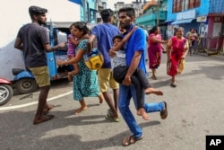 Sri Lankans living near St. Anthony's shrine run for safety after police found explosive devices in parked vehicle, which later exploded in Colombo, April 22, 2019.