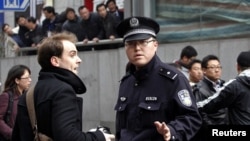 Policeman asks foreign journalist to leave area near Peace Cinema, after calls for a "Jasmine Revolution" protest, organized through internet, in downtown Shanghai, February 27, 2011.
