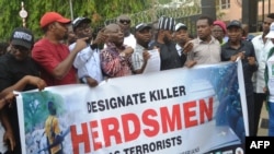 FILE - Demonstrators march and carry banner to protest bloody clashes between herdsmen and farmers in the vast central region that has claimed dozens of lives during a rally in Abuja, Nigeria, March 14, 2018.