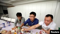 Han Liqun (C), a HR manager of RenRen Credit Management Co., drinks with his colleagues Kou Meng (L) and Ma Zhenguo after finishing work, after midnight, in Beijing, China, April 27, 2016. Office workers sleeping on the job is a common sight in China,...