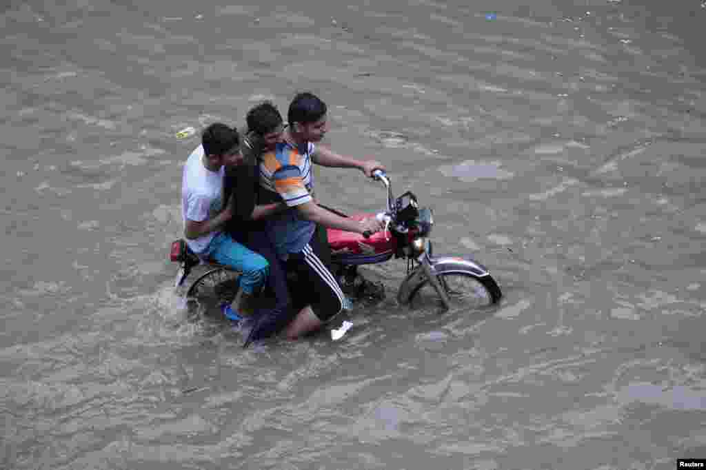 لاہور میں بارش کے پانی سے گزرتے موٹر سائیکل سوار