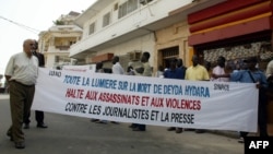 A group of 50 people hold a banner reading "Shed light on the death of Deyda Hydara. Stop assassinations and violence against journalists and the press," during a protest in front of Gambia's high commission, 22 December 2004 in Dakar.