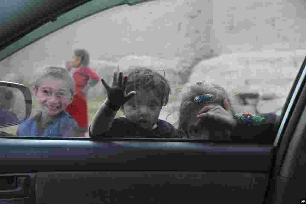 Children look into a window of a car on the outskirts of Jalalabad city east of Kabul, Afghanistan.