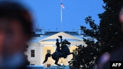 A row of police officers stand guard with the equestrian statue of former US President General Andrew Jackson behind, after protesters tried to topple it, at Lafayette square, in front of the White House, in Washington, DC on June 22, 2020. - A crowd of p