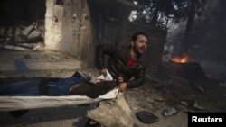 Un homme transporte un corps après un bombardement à Douma, en Syrie, le 7 novembre 2015.