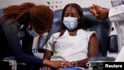 Mavis Knox prays next to nurse Sandra Lindsay, before Lindsay receives the second dose of a Pfizer coronavirus disease (COVID-19) vaccine, at Long Island Jewish Medical Center in the Queens borough of New York City, U.S., January 4, 2021. 