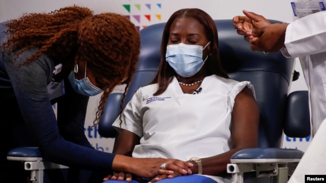 Mavis Knox prays next to nurse Sandra Lindsay, before Lindsay receives the second dose of a Pfizer coronavirus disease (COVID-19) vaccine, at Long Island Jewish Medical Center in the Queens borough of New York City, U.S., January 4, 2021. 