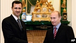 FILE - In this Dec. 19, 2006 file photo Vladimir Putin, then Russian President, right, and his Syrian counterpart Bashar Assad smile as they shake hands in Moscow's Kremlin. 