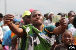 A Patriotic Front supporter proudly displays his identification and voter card, Lusaka, Zambia, JAn. 20, 2015. (Gillian Parker/VOA)