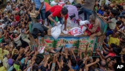 Rohingya Muslims, who crossed over from Myanmar into Bangladesh, stretch their arms out to collect food items distributed by aid agencies near Balukhali refugee camp, Bangladesh, Sept. 18, 2017. 