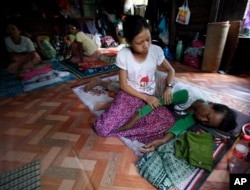 A daughter takes care of her HIV suffering mother as she rests in an HIV/AIDS shelter on the outskirts of Rangoon, Burma, Nov. 30, 2013.