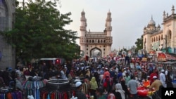 Warga berkerumun di pasar di depan masjid Charminar yang terkenal di bulan suci Ramadan di Hyderabad, India, mengabaikan protokol kesehatan, Kamis, 6 Mei 2021. (Foto AP / Mahesh Kumar A.)