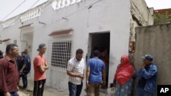 Neighbors gather at the entrance of a house in which elite police squads killed two armed terrorists and arrested 16 others in an operation in the Menihla area, outside Tunis, May 11, 2016.