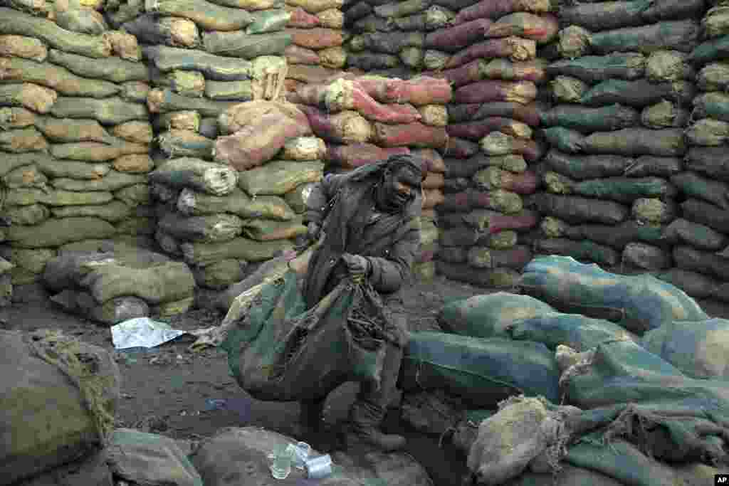 A laborer moves a sack of charcoal at a shop, in Kabul, Afghanistan.