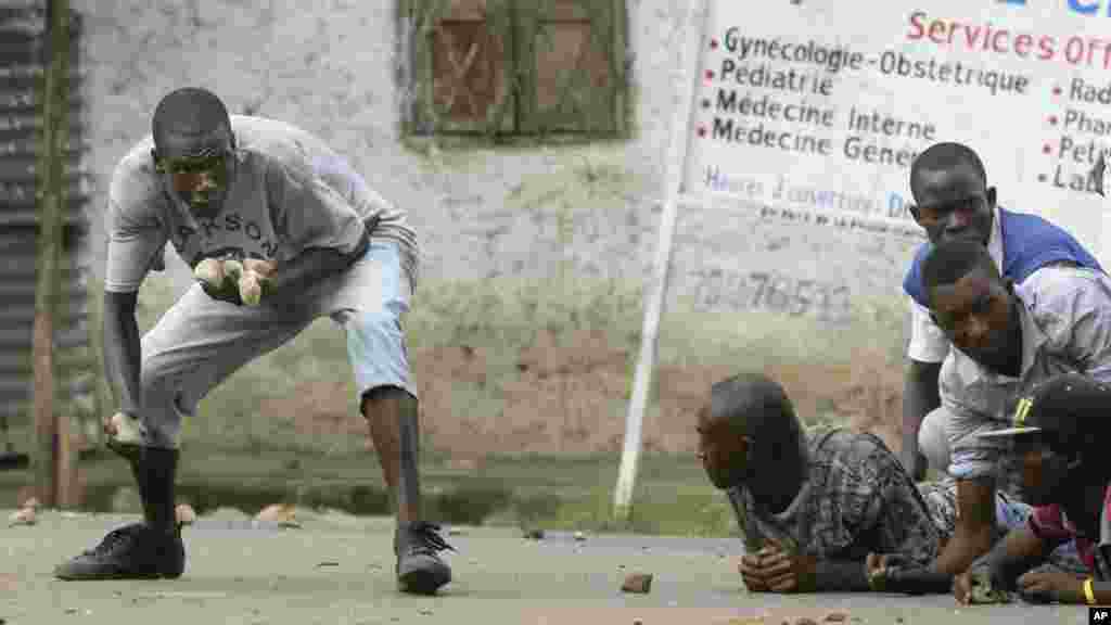 Des manifestants s&#39;abritent et lancent des pierres contre la police à Bujumbura, le 20 mai 2015