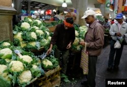 FILE - A vendor shows vegetables to customers at the market in Port Louis on the Indian Ocean island of Mauritius, Aug. 5, 2015.