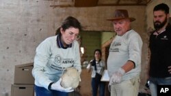 Rogelio Goiburu y Liliana Bogarin, miembros de la oficina estatal Memoria y Reparación Histórica del Ministerio de Justicia, inspeccionan un cráneo que forma parte de restos hallados bajo el baño de una casa en Ciudad del Este, Paraguay, el martes 10 de septiembre de 2019. 