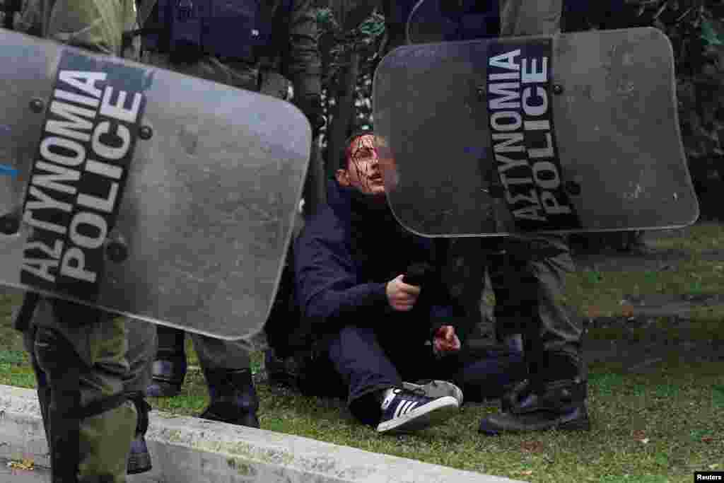 An injured demonstrator is detained by riot police during an anniversary rally marking the 2008 police shooting of 15-year-old student Alexandros Grigoropoulos, in Athens, Greece.