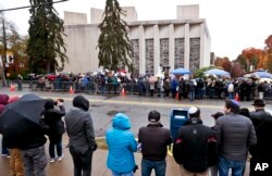 People line both sides of the street as they gather outside the Tree of Life synagogue for a service on Nov. 3, 2018, in Pittsburgh. About 100 people gathered in a cold drizzle for what was called a "healing service" outside the synagogue that was the scene of a mass shooting a week ago.