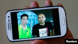 Peter Chong sostiene un teléfono en el que aparece junto al capitán Zaharie Ahmad Shah (derecha).