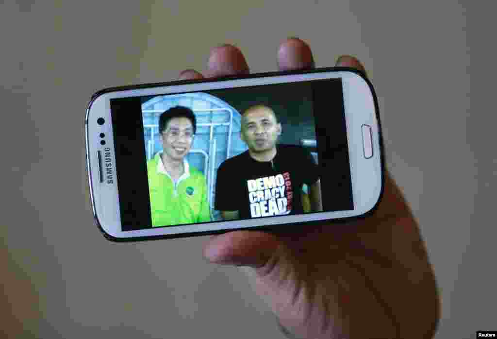 Anh Peter Chong cho xem hình chụp chung với cơ trưởng Zaharie Ahmad Shah (phải) trên iPhone trong một cuộc phỏng vấn với hãng tin Reuters tại một khách sạn ở Sepang.
