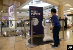 A boy gets to know Pepper the robot at the Westfield Mall in San Francisco, Dec. 22, 2016. Pepper has trouble understanding what people are asking, requiring shoppers to type in their requests for mall directions on a tablet mounted on the robot's chest.