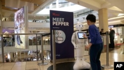 A boy gets to know Pepper the robot at the Westfield Mall in San Francisco, Dec. 22, 2016. Pepper has trouble understanding what people are asking, requiring shoppers to type in their requests for mall directions on a tablet mounted on the robot's chest.