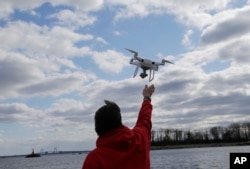FILE- A drone operator helps to retrieve a drone after photographing over Hart Island in New York, April 29, 2018.